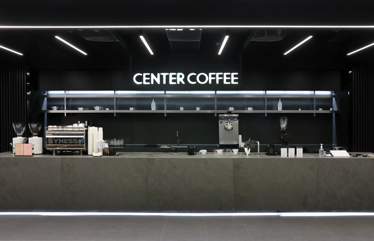 Official interior of Center Coffee Seoul Station with illuminated brand signage behind the counter